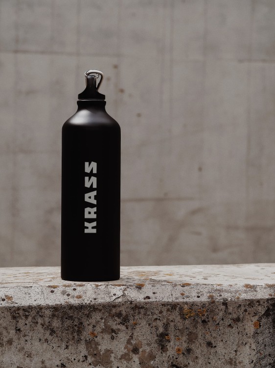 Butelka aluminiowa z logotypem marki stojąca na murku.