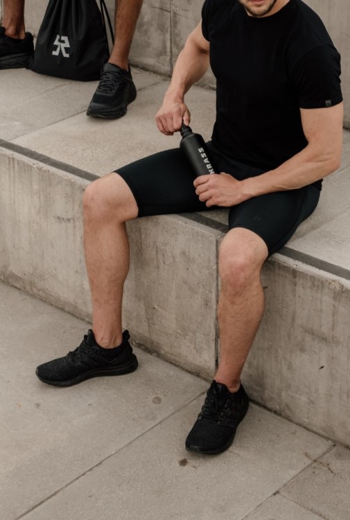 Mężczyzna siedzący na murku z butelką w ręku.